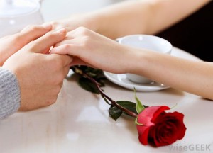 man-and-woman-holding-hands-on-table-with-red-rose